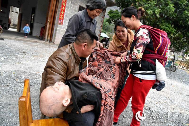 梁天依在嫂子苏利春（右三）、侄子梁培衡（左一）、侄媳妇韦秋仕（右二）、侄孙媳妇韦寒静（右一）的陪伴下，到室外呼吸新鲜空气。（高东风/摄）